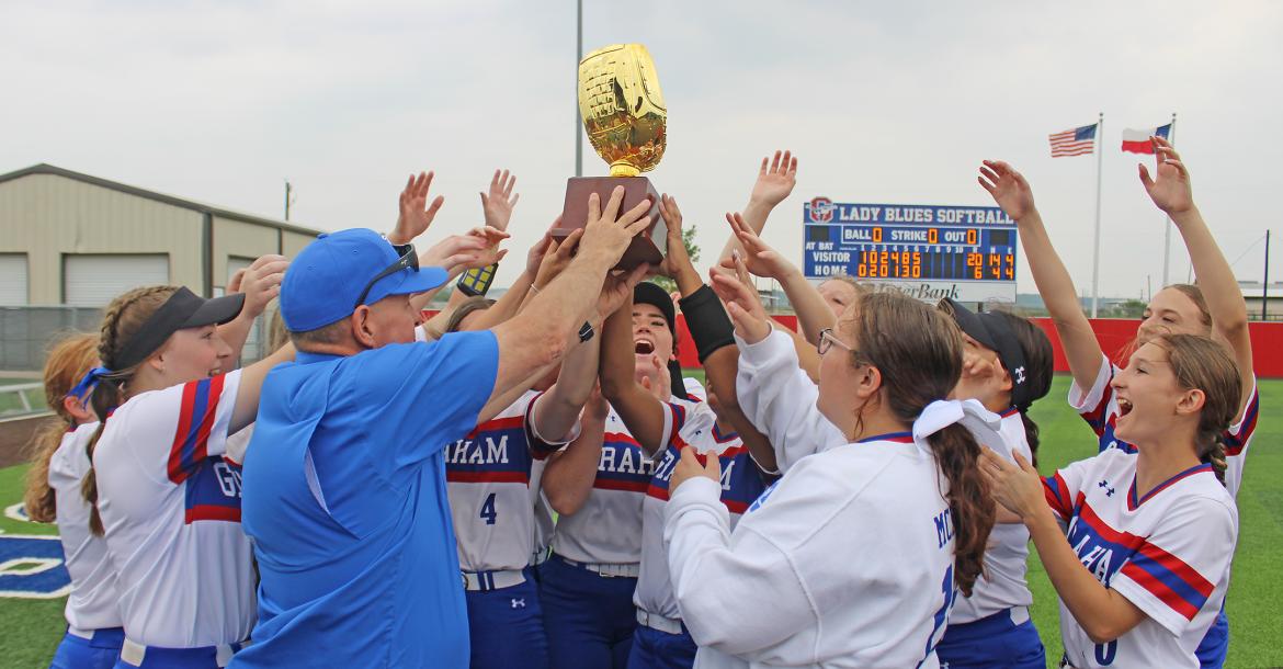 (MIKE WILLIAMS | CONTRIBUTED PHOTO) The Graham Lady Blues hoist a bi-district championship trophy after they defeated Lubbock Estacado in two straight games by scores of 11-1 and 20-6.