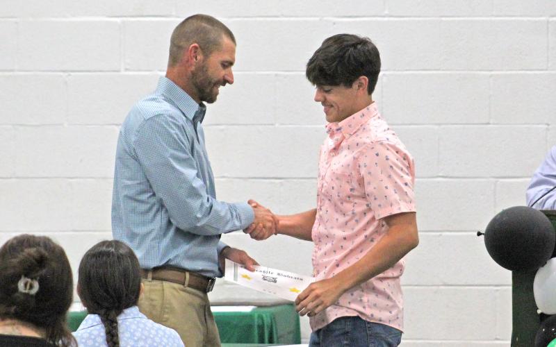 (TC GORDON | THE GRAHAM LEADER) Freshman Keyton Newland (middle) shakes hands with coach James King at the Newcastle sports banquet held in the gym Tuesday, May 21. Athletes were honored from every sport throughout the school year.