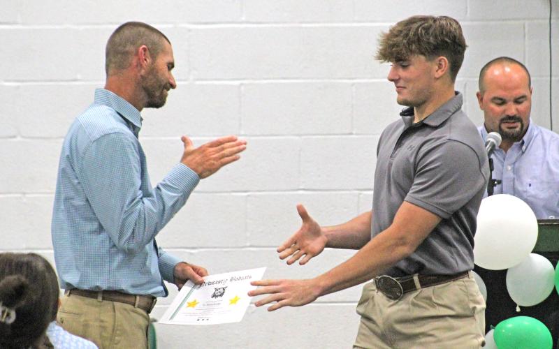 (TC GORDON | THE GRAHAM LEADER) Senior Ty Strawbridge shakes hands with coach James King as part of the football recognitions at the Newcastle sports banquet Tuesday, May 21.