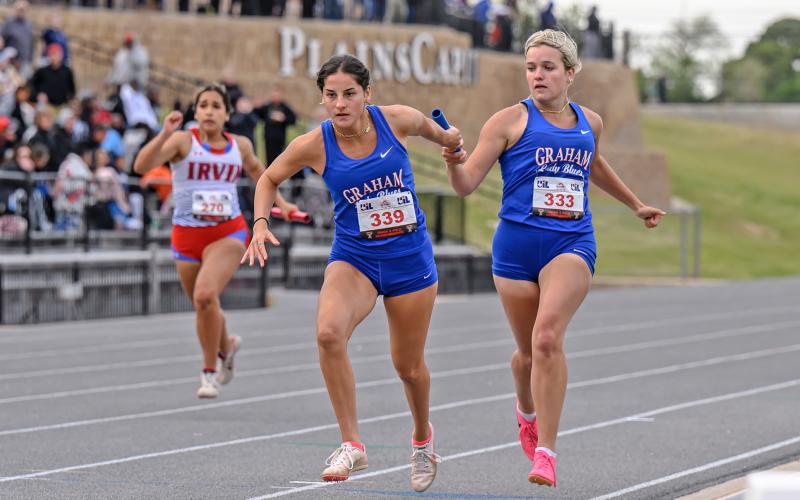 (DAVID FLYNN | CONTRIBUTED PHOTO) Kaden Atwood (right) passes the baton to teammate Georgia Martin (left) during one of the relay races at the regional meet in Lubbock. The Lady Blues’ relay teams finished sixth in the preliminaries in each of their races.